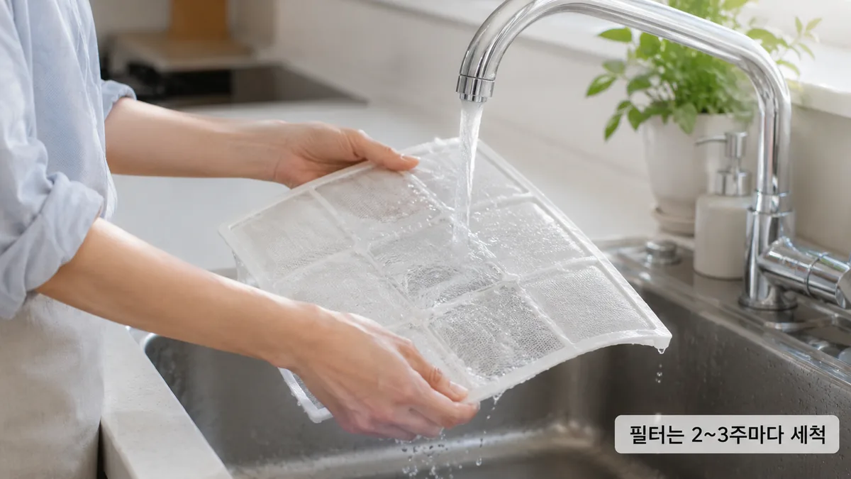 싱크대에서 에어컨 필터를 흐르는 물로 세척하는 모습